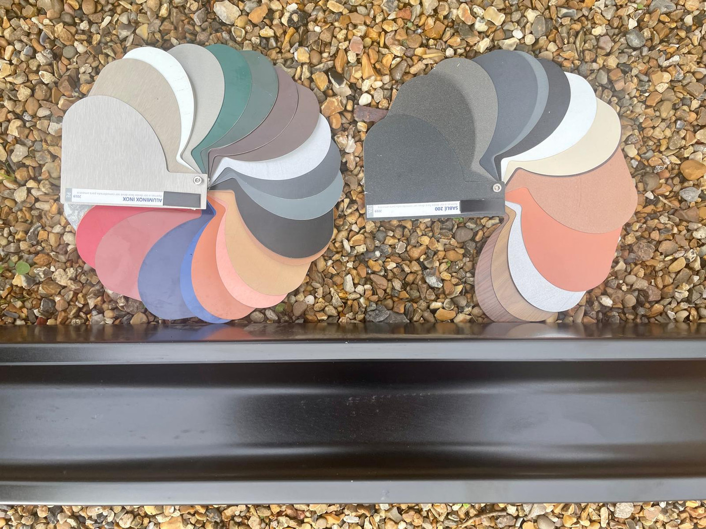 Aluminium guttering colour samples held against a fitted gutter